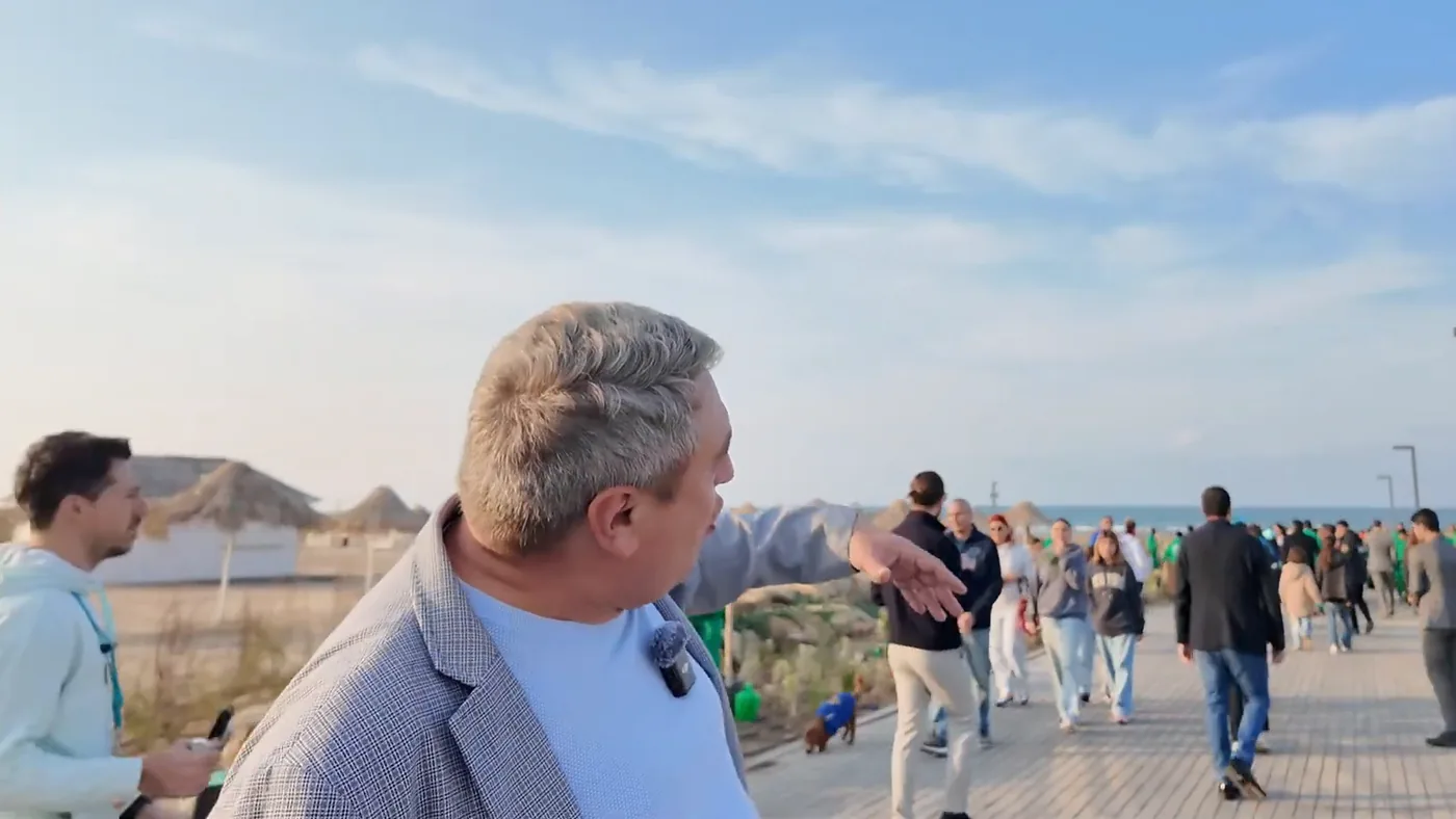 אורחי הטקס הולכים לאורך השדרה אל הים, ומולם שמשיות הקש של החוף